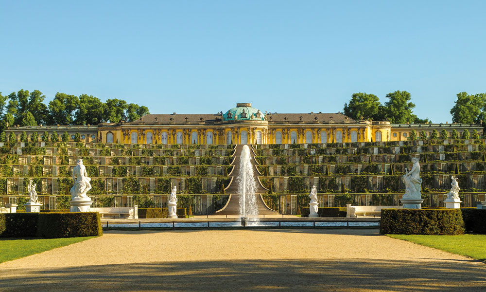 Wegen der reizvollen Lage und der schönen Aussicht entschied sich Friedrich der Große, auf dem „Wüsten Berg“ bei Potsdam ein Lustschloss zu erbauen. Durch die Kolonnaden des Ehrenhofes erblickt man den Ruinenberg.